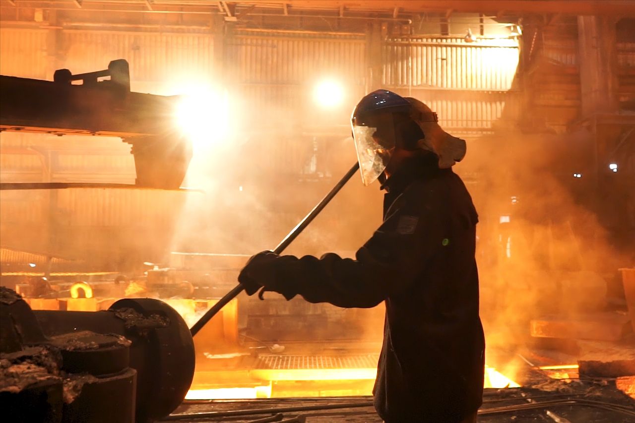 Man in beschermpak giet ijzer in staalfabriek