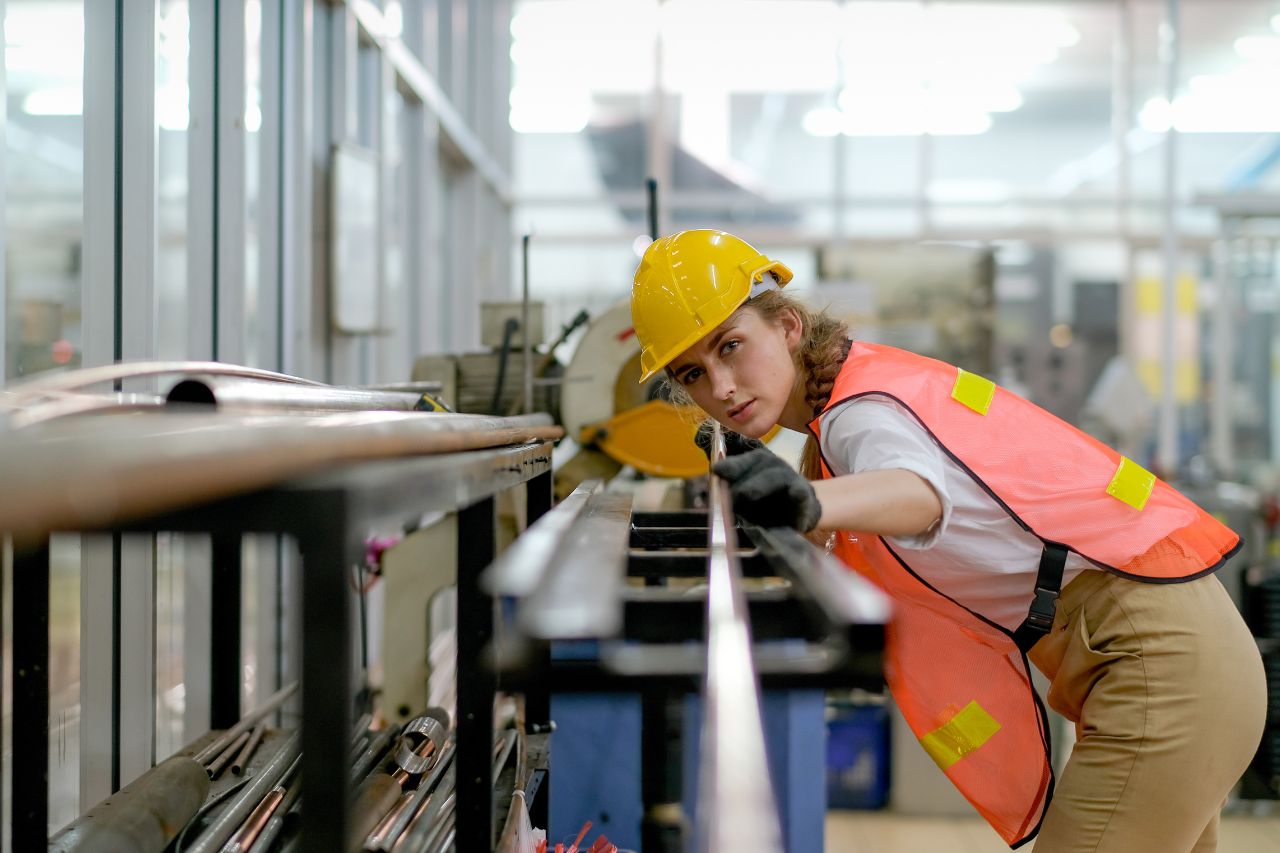 Vrouw kijkt koperen buis na in fabriek